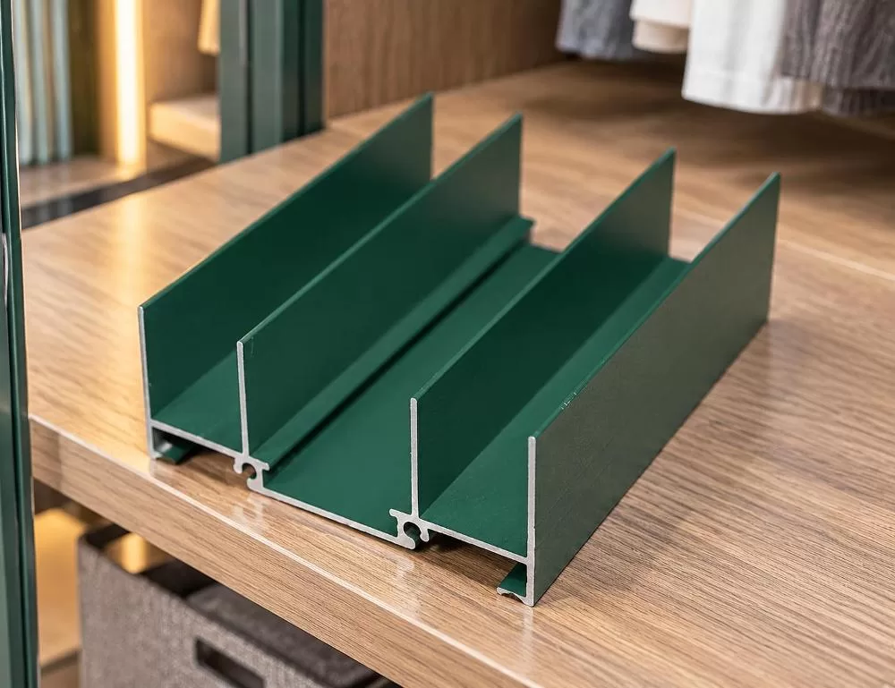 Cross-section sample of an extruded aluminium wardrobe profile in matte dark green powder coating
